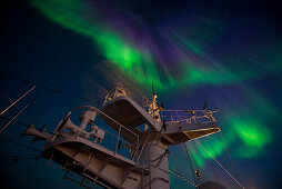 The northern lights (also polar lights or Aurora Borealis) light up the sky just after sunset, seen from aboard expedition cruise ship MS Bremen (Hapag-Lloyd Cruises), between Northeast Cape and Cape Ossory, Nunavut, northern Canada, North America