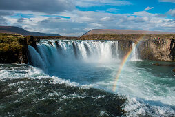Ein heller Regenbogen erstreckt sich über den 12 Meter hohen Goðafoss (Wasserfall der Götter), nahe Seyðisfjörðdur, im Osten von Island, Europa