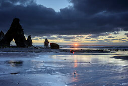 Sonne geht bei Felsbögen von White Cliffs im Meer unter, Tongaporutu, Taranaki, Nordinsel, Neuseeland