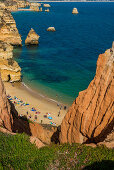 Badegäste am Strand zwischen steilen Felsen, Praia do Camilo, Lagos, Algarve, Portugal