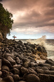 USA, Hawaii, The Big Island, surfer watches the waves on a rocky shoreline at the Hakalau River mouth