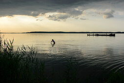 Woman goes swimming and anglers footbridge on the lagoon side in Lieper angle, Usedom, Baltic Sea coast, Mecklenburg-Vorpommern, Germany