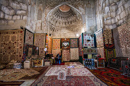 Uzbek woman sells textiles in Abdulasis Khan Madrassa in Bukhara, Uzbekistan, Asia