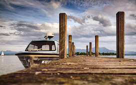 View of a boat on a jetty, in the background the Fraueninsel and the Chiemgau Alps on a summer evening, Gstadt am Chiemsee, Upper Bavaria, Germany