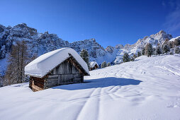 Snow-covered alpine huts with Geisler range in background, Medalges, Natural Park Puez-Geisler, UNESCO world heritage site Dolomites, Dolomites, South Tyrol, Italy
