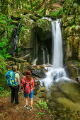 Zwei Frauen beim Wandern blicken auf Wasserfall, Höllbach-Wasserfall, Albsteig, Schwarzwald, Baden-Württemberg, Deutschland