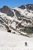 Man and woman hiking descending through snow to hut refuge Viso, Giro di Monviso, Monte Viso, Monviso, Cottian Alps, France