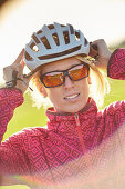 Young  woman puts on her bicycle helmet, Muensing, bavaria, germany