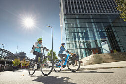 junge Frau und junger Mann Paar auf eBikes in der Stadt, München, Bayern, Deutschland