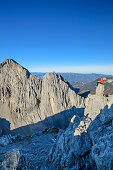 Mann sitzt auf Felsturm und blickt auf Felswände der Hinteren Karlspitze, von Hintere Goinger Halt, Wilder Kaiser, Kaisergebirge, Tirol, Österreich