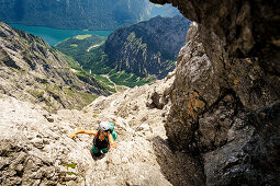 Young woman with climbing gear ascends the Watzmann east face, views to lake Königsee, St. Bartholomä, Berchtesgaden, Bavaria, Germany
