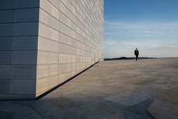 fman with sunglasses walks at roof of opera, the New Opera House in Oslo, Norway, Scandinavia, Europe