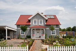 Graues zweistöckiges Einfamilienhaus mit einer Gaube und einem roten Dach im nordischen Stil mit Holzfassade, Korbach, Hessen, Deutschland, Europa