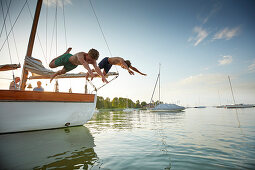 Zwei Jugendliche springen vom Boot, Segeln auf dem Ammersee, Bayern Deutschland
