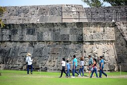Tourists in front of a stepped temple with stone sculptures on the pre-Columbian archaeological site of Xochicalco at Cuernavaca, Mexico