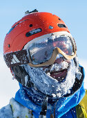 Portrait eines Extremskifahrers mit Helm und Skibrille, Schnee und Eis im Gesicht