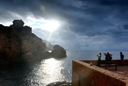 Tourists marvel at the sunset at Porto on the Gulf of Porto, western Corsica, France