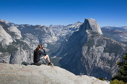 Frau fotografiert den Half Dome im Sommer bei blauem Himmel, Yosemite Nationalpark, USA\n