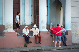 Männer im Gespräch auf der Straße von Cienfuegos, Kuba\n