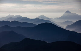 Mountain silhouettes of the Bavarian Prealps on Lake Walchensee with fog, from Jochberg