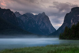 Morning fog on Toblacher See at sunrise in the Dolomites, South Tyrol