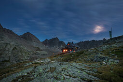 Dramatische Wolken mit beleuchteter Nossberger Hütte im Gradental bei Nacht, Nationalpark Hohe Tauern, Österreich