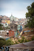 Police storm a dilapidated neighborhood, street art, colorful houses and church tower in Valparaiso, Chile, South America
