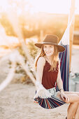 Woman sitting in hammock in front of caravan in Joshua Tree National Park, Joshua Tree, Los Angeles, California, USA, North America