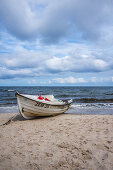 Fishing boat on the Baltic Sea beach with cloudy, dramatic sky and rough sea, Usedom, Mecklenburg-Western Pomerania, Germany