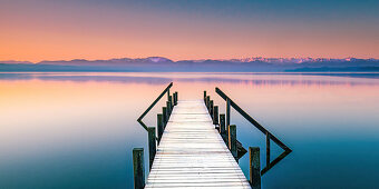 Winter morning with a snow-covered jetty at sunrise on Lake Starnberg, Bavaria, Germany