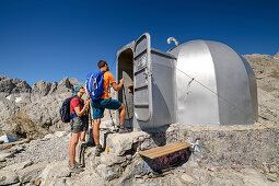 Drei Personen beim Wandern stehen vor Hütte Cabana Veronica, Cabana Veronica, Picos de Europa, Nationalpark Picos de Europa, Kantabrisches Gebirge, Kantabrien, Spanien