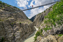 Woman while hiking stands on Aletsch suspension bridge, Aletsch suspension bridge, UNESCO World Natural Heritage Jungfrau-Aletsch, Bernese Alps, Switzerland