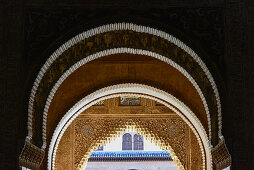 Several arches inside and the view into the courtyard of the Alhambra, Granada, Andalusia, Spain