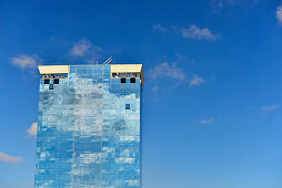 Hochhaus mit Glasfassade, in der sich der blaue Himmel und einige Wolken spiegeln, Barcelona, Katalonien, Spanien