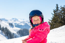 Child in the snow in St. Johann in Tirol with Kitzbühel Alps in the background, St. Johann, Tyrol, Austria