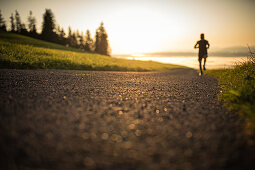 Läufer auf einem leeren Weg in den Morgenstunden, Allgäu