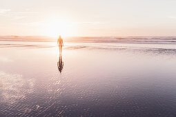 Frau spaziert im Sonnenuntergang am Strand, Portugal