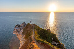 Eine Frau steht an der Alabasterküste bei Étretat und blickt auf das Meer, Normandie, Frankreich