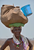 Angola; im westlichen Teil der Provinz Cunene; Frau an der Straße; mit Gepäck auf dem Kopf tragend