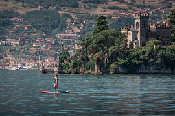 Frau paddelt auf SUP Board vor Schloss Castello della Isola di Loreto auf Insel im Iseosee in Italien