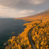Road through landscape with lake in Stora Sjöfallet National Park in autumn in Lapland in Sweden from above