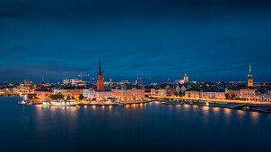 Beleuchtete Skyline von Stockholm bei Nacht mit Kirche Riddarholmskyrkan auf Altstadtinsel Gamla Stan in Schweden\n