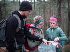 Wandergruppe liest Wanderkarte beim Wandern im Wald im Tiveden Nationalpark in Schweden\n