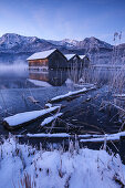 Wooden huts and jetty on the Kochelsee at the blue hour in winter, in the foreground the icy lake shore, Schlehdorf, Bavaria, Germany, Europe