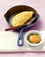 Omelett in einer Pfanne und gestocktes Ei im Förmchen