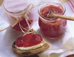 Strawberry jam in two jars and on bread