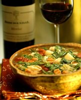 Seafood soup with noodles, vegetables and pesto; red wine