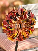 Wreath of autumn leaves and rose hips on chair back