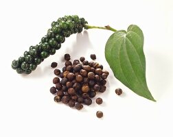Bunch of green peppercorns with leaf and loose peppercorns