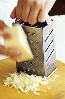 Käse wird mit Käsereibe gerieben